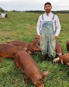 farmer stands with pastured hereford hampshire cross pigs