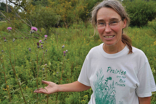 Mary Damm plant ecologist standing in thistle