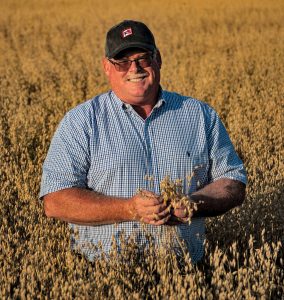 Wayne Koehler farmer in mature field of oats iowa