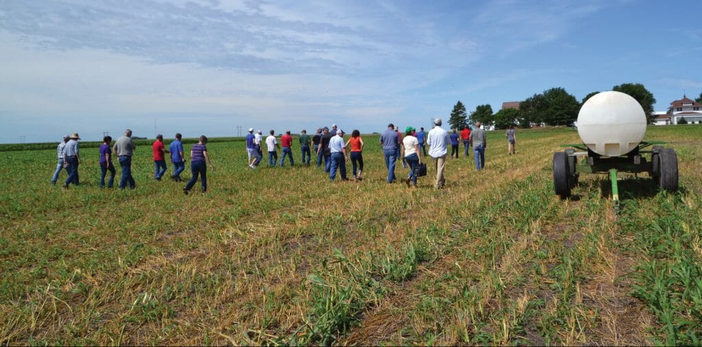 Guests at AJ and Kellie Blair field day in 2018 walk back through rye field that was baled earlier