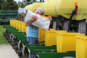 Dick Sloan loads treated corn seed into his planter in May 2018