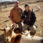 Matt and Jocelyn Vermeersch of Mud Ridge Farm and his partner crouch behind some of their goats