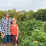 Scott & Megan Booher pose for the camera in a field of hemp on their farm.