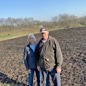 Beth and Rick McGeogh in front of their newly burned prairie. Burning is essential for the overall health of many prairie plants.