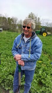 Dick Sloan standing in a strip of red clover in May.